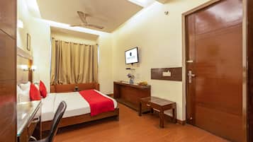A hotel room with a bed, desk, chair, and a television on the wall.