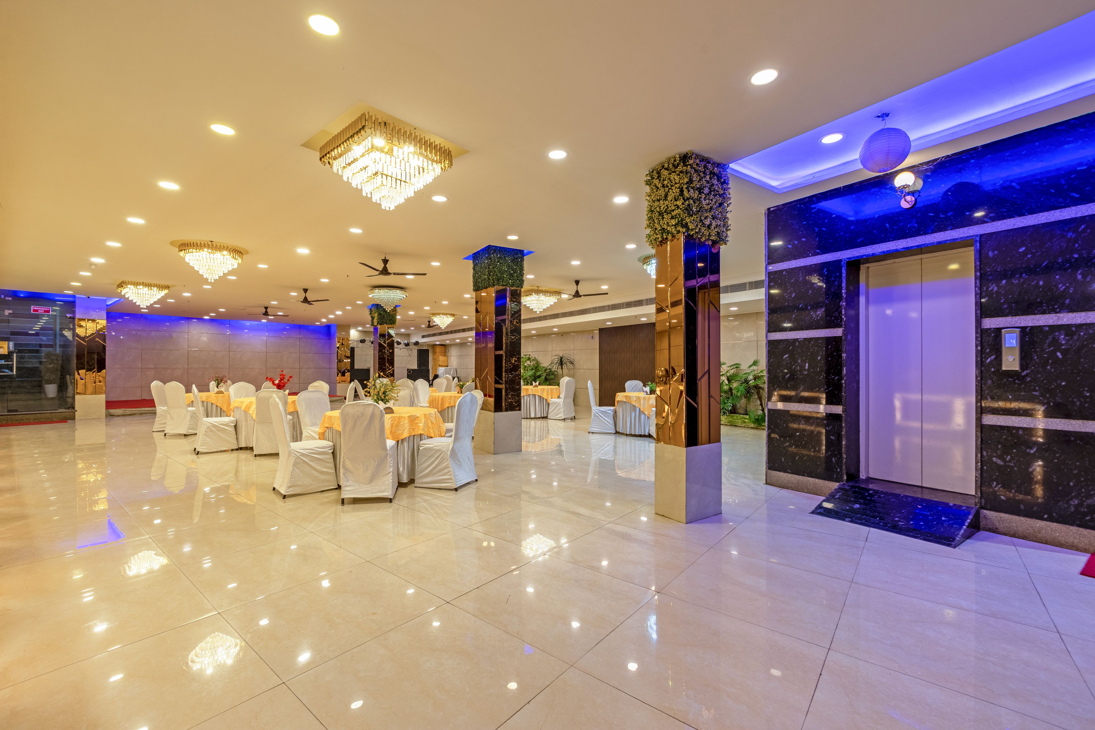 A spacious indoor area with multiple tables and chairs, ceiling fans, and decorative lighting fixtures.
