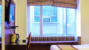 A hotel room with a bed, a desk, a television, and a window with curtains.