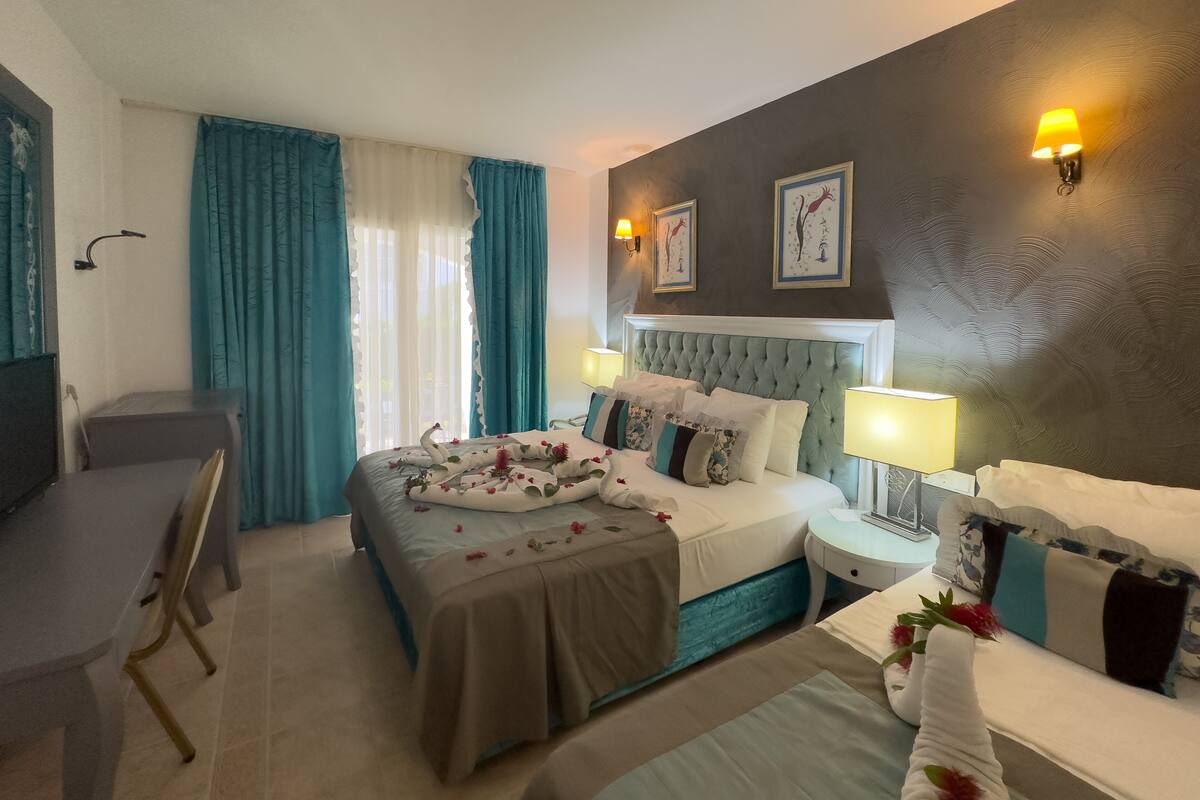 Quarto de hotel com uma cama, duas mesas de cabeceira, uma escrivaninha e uma cadeira.