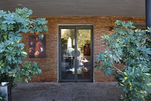 Un edificio con fachada de ladrillo, puertas de cristal grandes y plantas en macetas a la izquierda.
