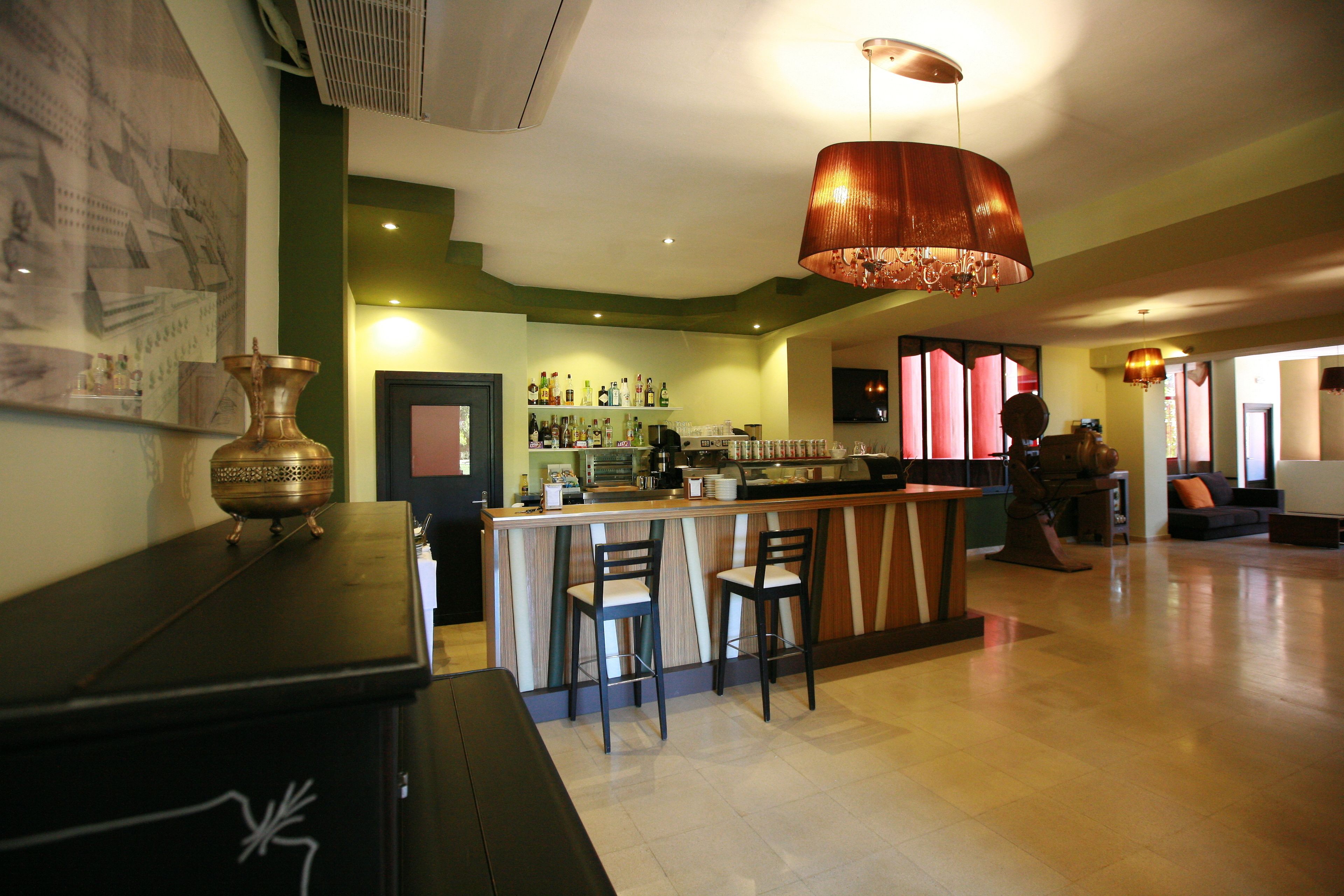 A bar area with a wooden counter, two bar stools, and a large copper pendant light.