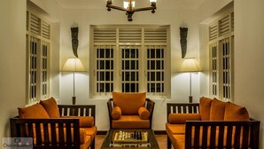 A room with a central sofa, two armchairs, a coffee table with chess, and a chandelier. - Clovefield Villa (Hatton)