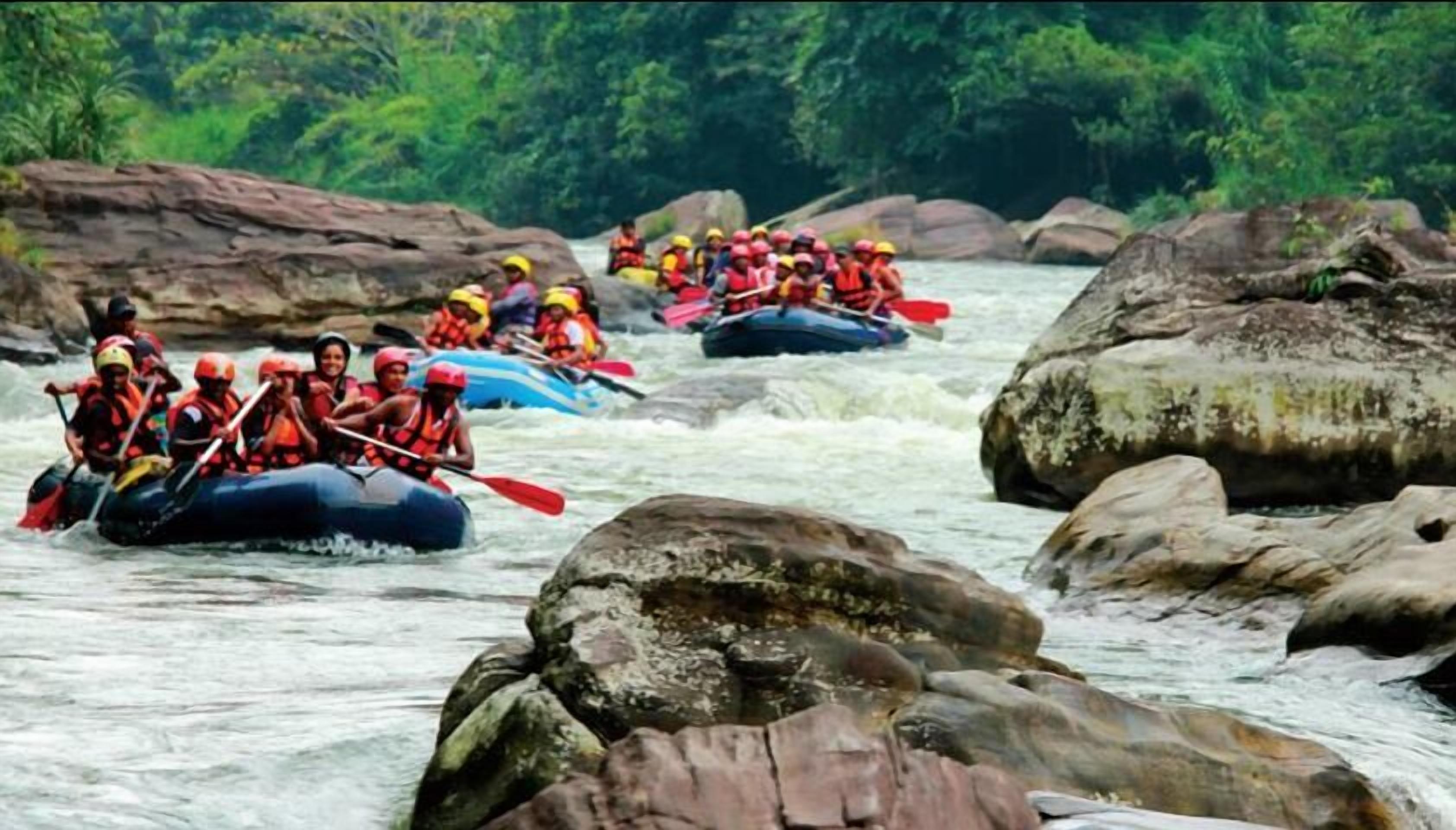 Un grupo de personas hacen rafting en un río rodeado de rocas y vegetación.