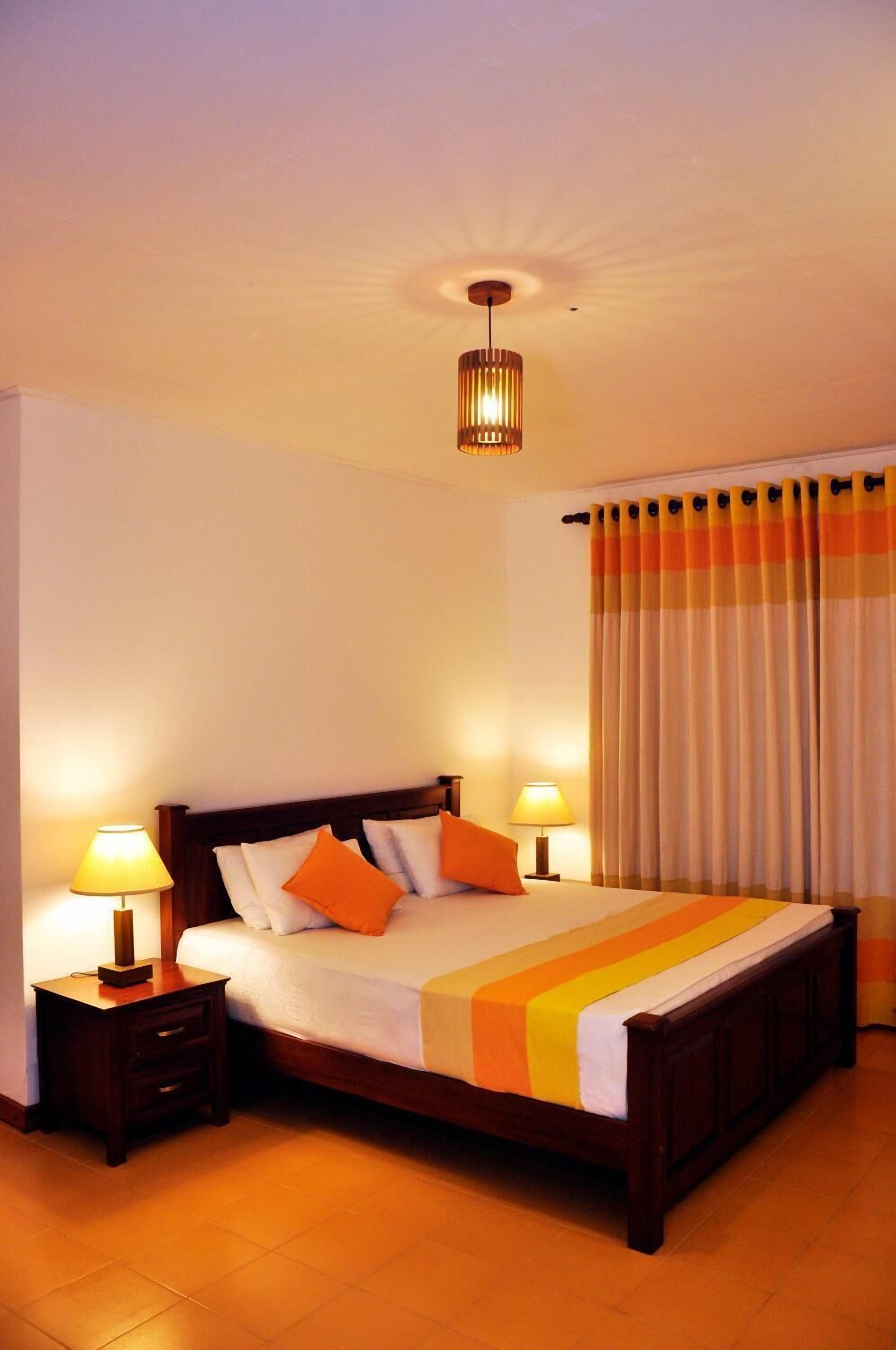 A neatly made bed with a striped bedspread, two bedside lamps, and a wooden headboard.