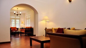 A living room with a sofa, chairs, a table, and a lamp. - Clovefield Villa (Hatton)