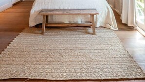 A bedroom with a wooden ceiling, a bed with a canopy, a wooden bench, and a woven rug. - Castaway Resort (Lembongan Island)