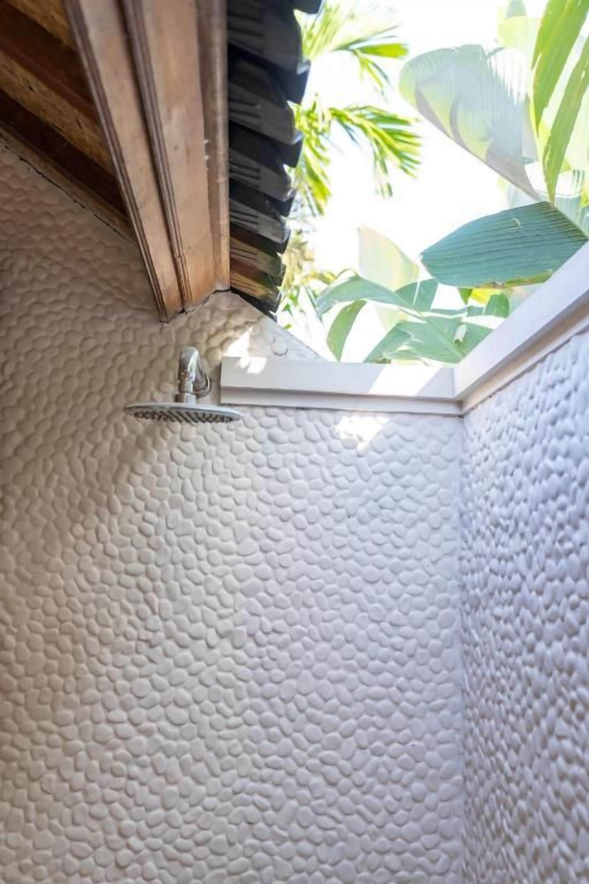 A textured white wall with a window corner and a metal faucet.
