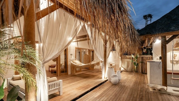 A wooden deck with a hammock, white curtains, and a thatched roof structure. - Castaway Resort (Lembongan Island)