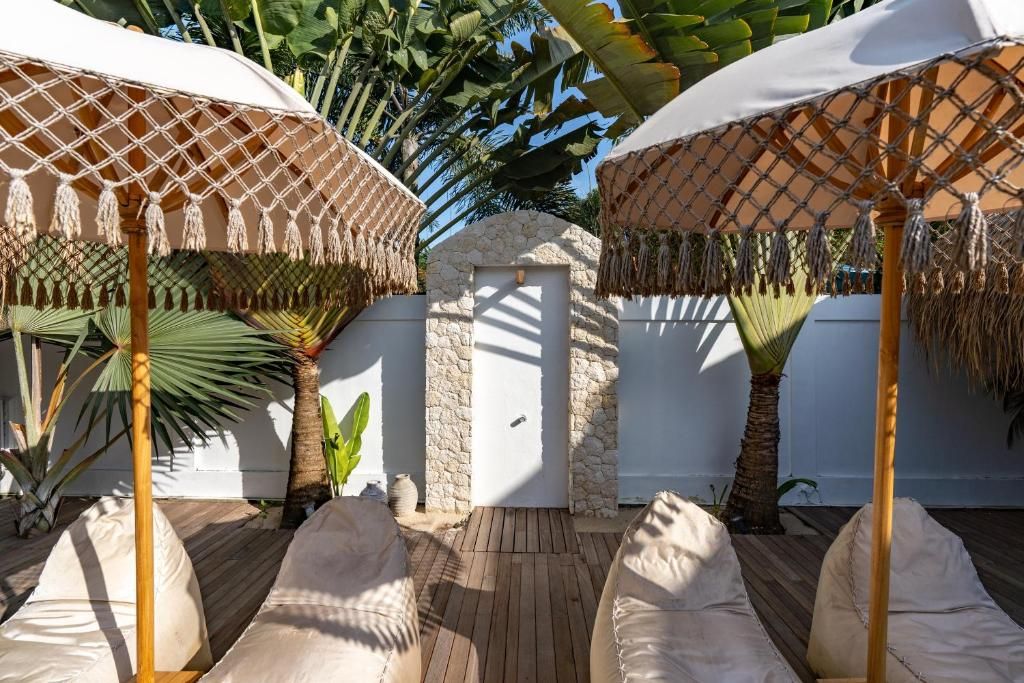 Un patio con dos sillones blancos acolchados, un muro de piedra y una puerta.