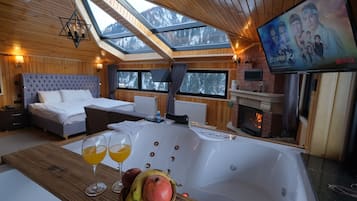 A cozy room with a large bed, a bathtub, and a fireplace.