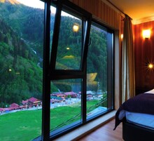 Una habitación con un ventanal amplio que ofrece vistas a una zona montañosa y un pequeño pueblo en la falda.
