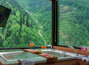 Un baño con un amplio ventanal que ofrece vistas a un valle verde exuberante.