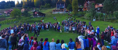 A large group of people gathered on a grassy hill with buildings in the background.