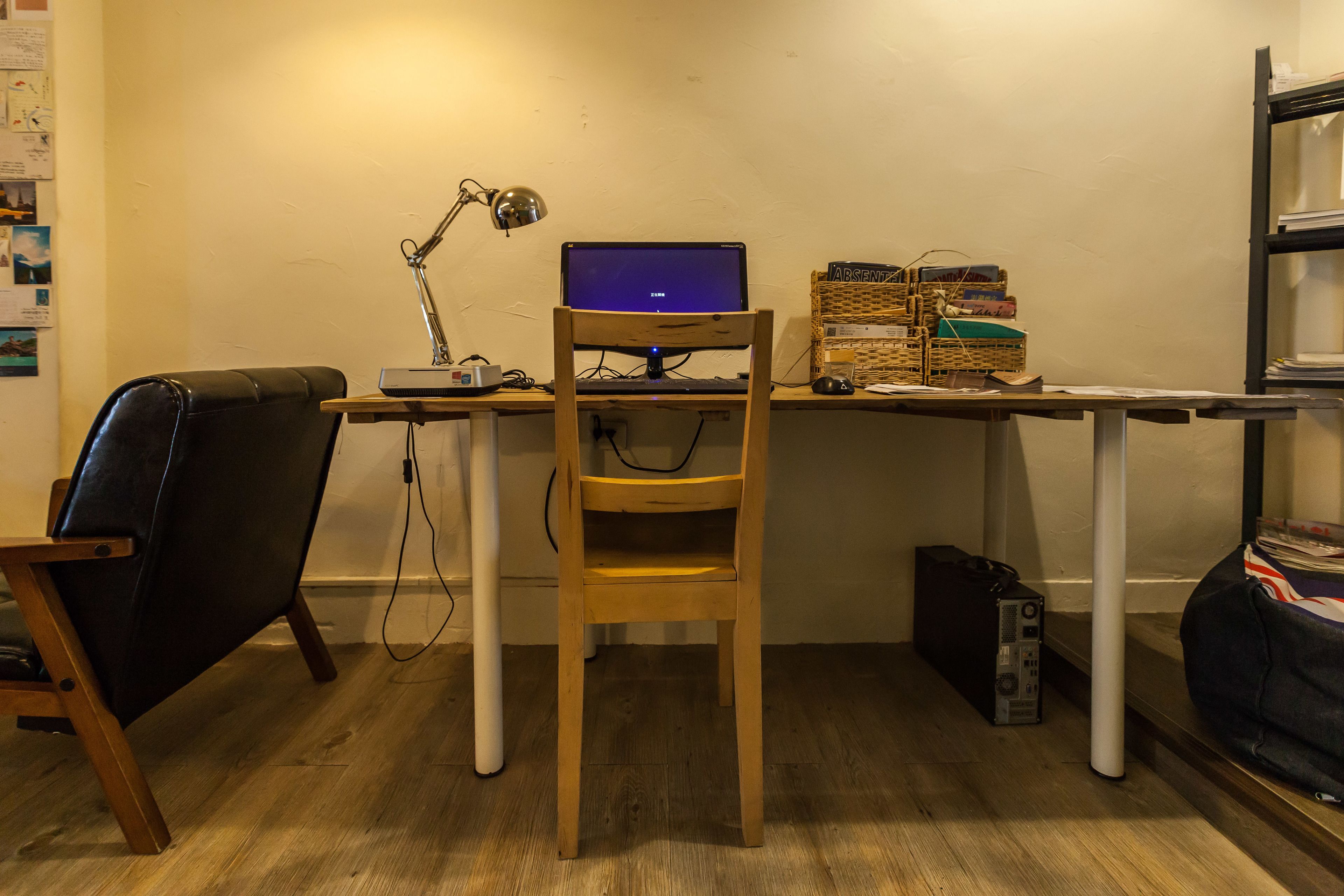 A small office space with a desk, a laptop, a chair, a lamp, and a shelf with books.