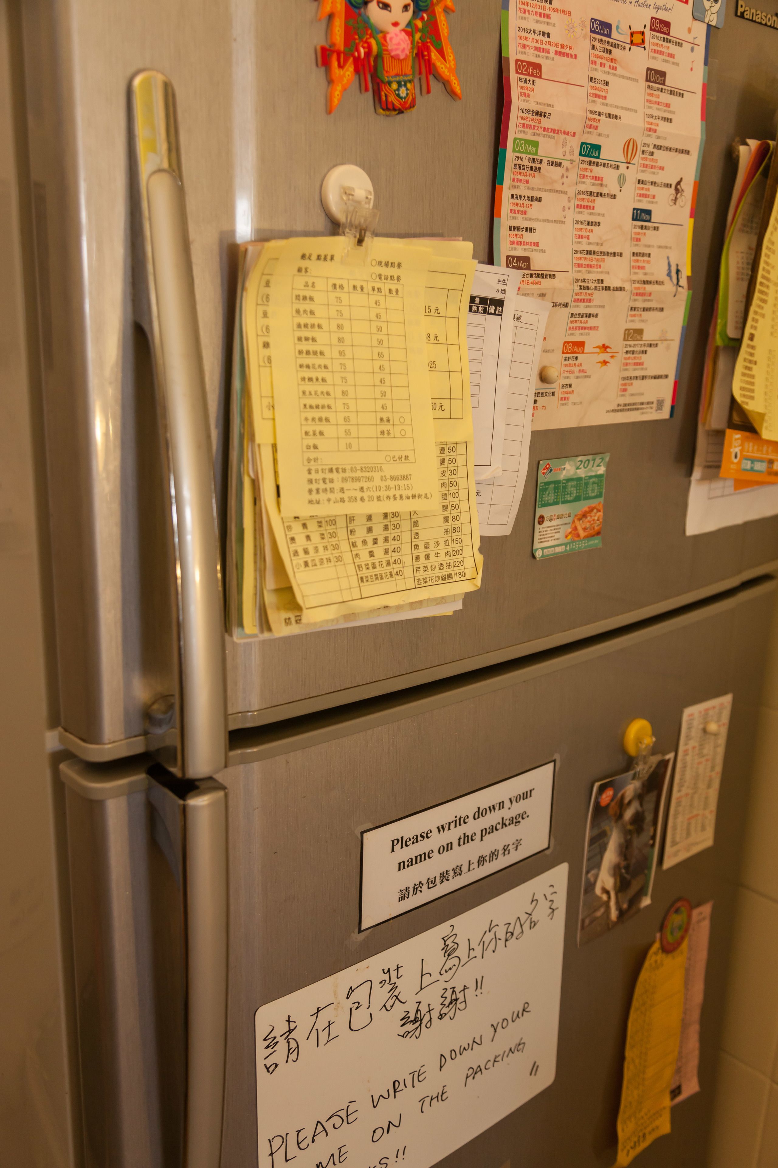 A refrigerator with various papers and magnets, including a note requesting to write names on packages.