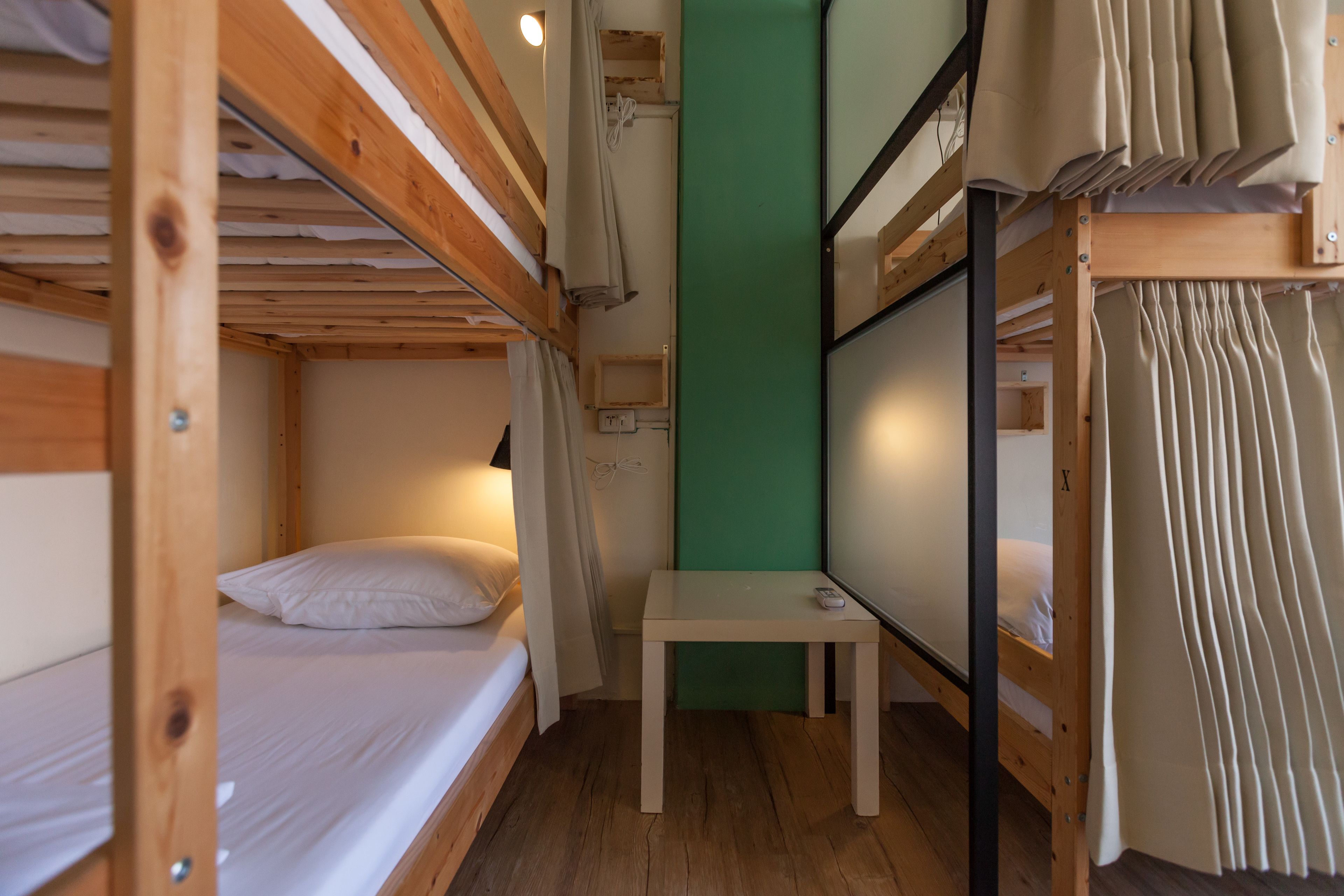 A compact room with two bunk beds, a small table, and a green accent wall.