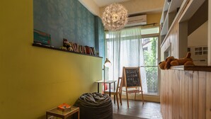 Um quarto aconchegante com um bean bag, uma pequena mesa com uma caixa, um quadro negro e um lustre.