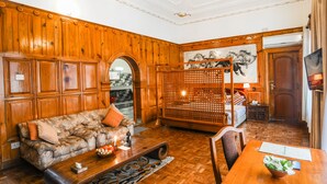 Una habitación con pared de paneles de madera, un sofá con cojines, una mesa de comedor con un cuenco de flores y una biombos de madera.