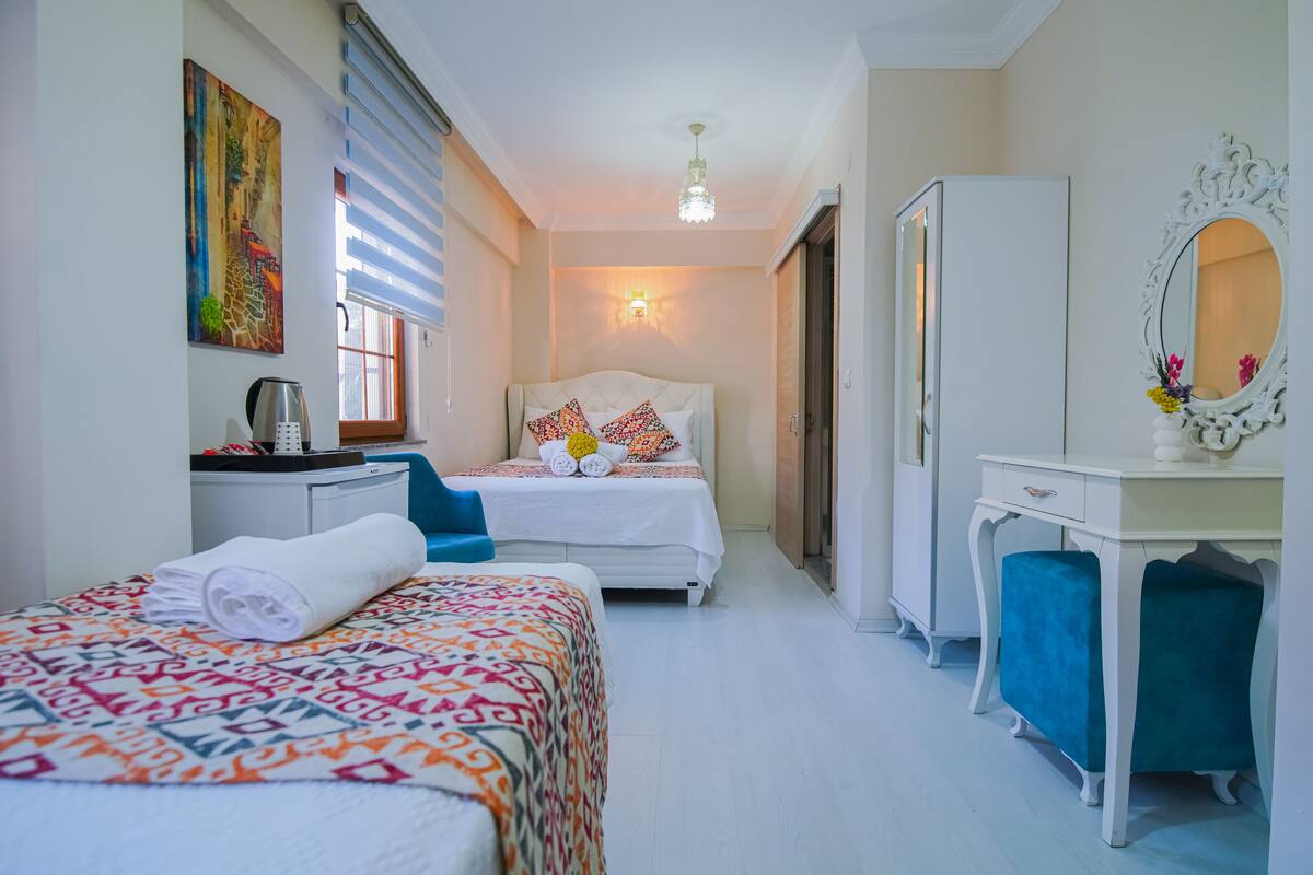 A hotel room with two beds, a desk, a wardrobe, and a mirror.