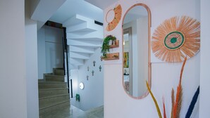 Een modern interieur met een trap, een wandspiegel en decoratieve muurkunst.