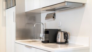A modern kitchen with a stainless steel range hood, a coffee maker, and a kettle on the countertop.