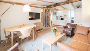 A modern living room with a wooden ceiling, a dining area, a sofa, and a coffee table.