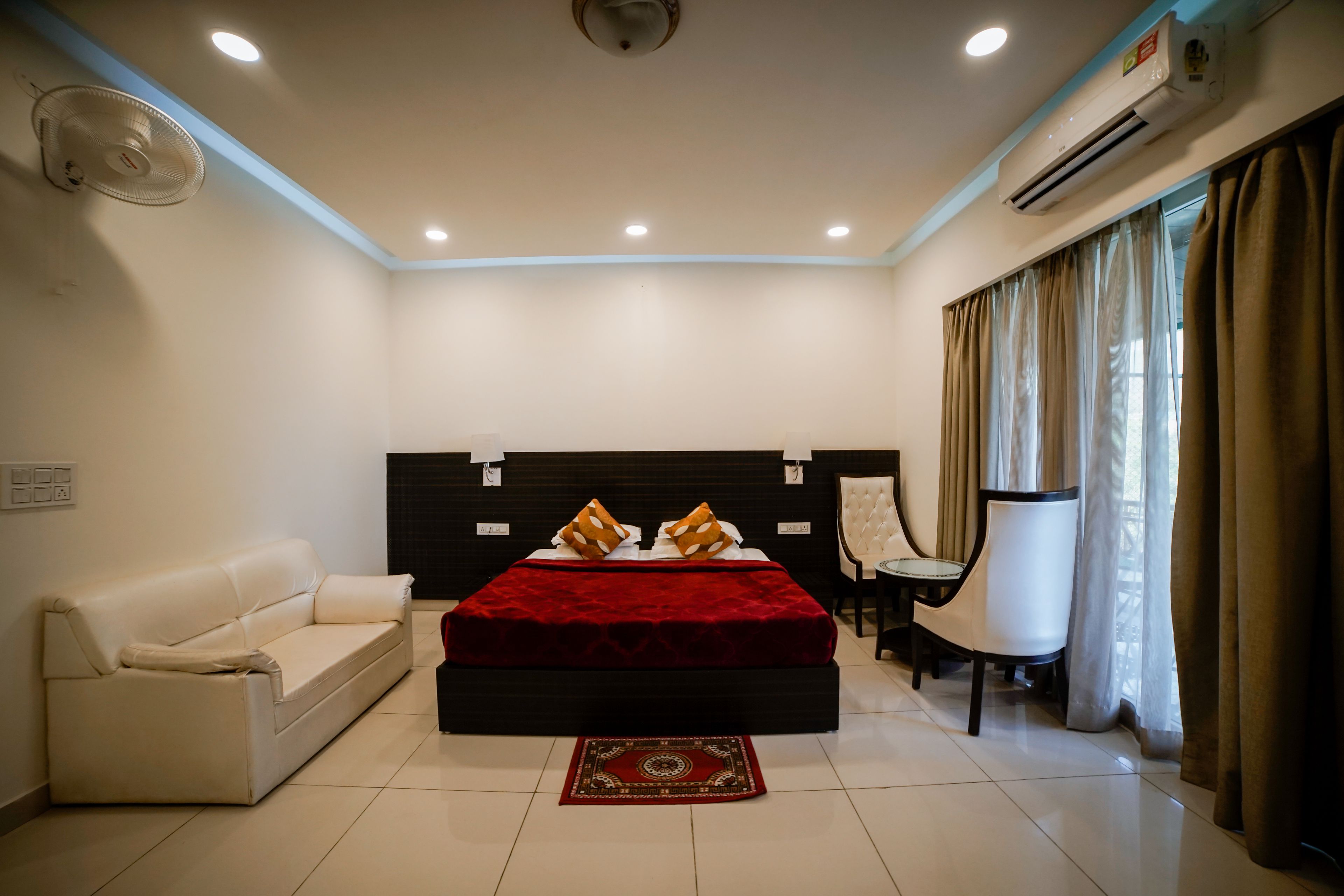 Un dormitorio con cama, sofá, sillón y equipo de aire acondicionado.