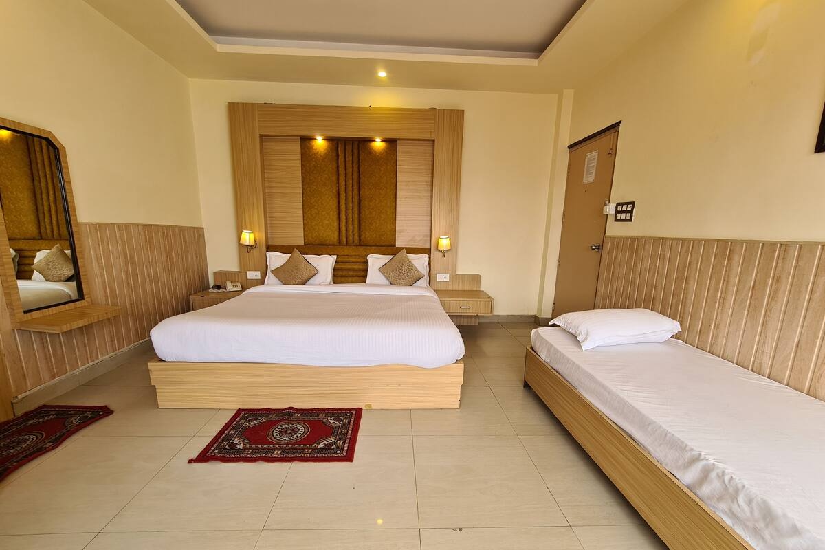 A hotel room with a large bed, two bedside tables, a mirror, and a wooden headboard.