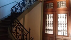 A staircase with ornate black metal railings and a wooden door with decorative glass panels. - Chambre D'hôte du Château (Dourdan)