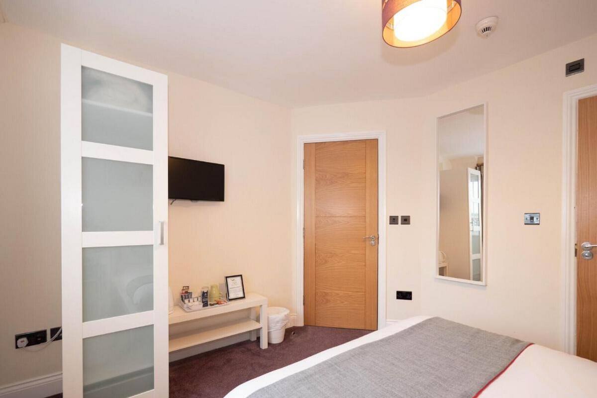 Une chambre à coucher avec un lit, une armoire, une télévision, un miroir et une porte.
