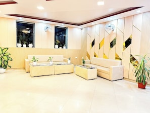 A modern lobby with a sofa set, a coffee table, and potted plants.