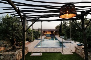 Una piscina al aire libre, sillones reclinables de piscina