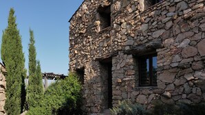 A stone building with a wooden porch and a window. - Pozzo di Mastri (Figari)