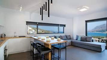 Una cocina moderna con comedor, ventanas amplias y vista al mar.