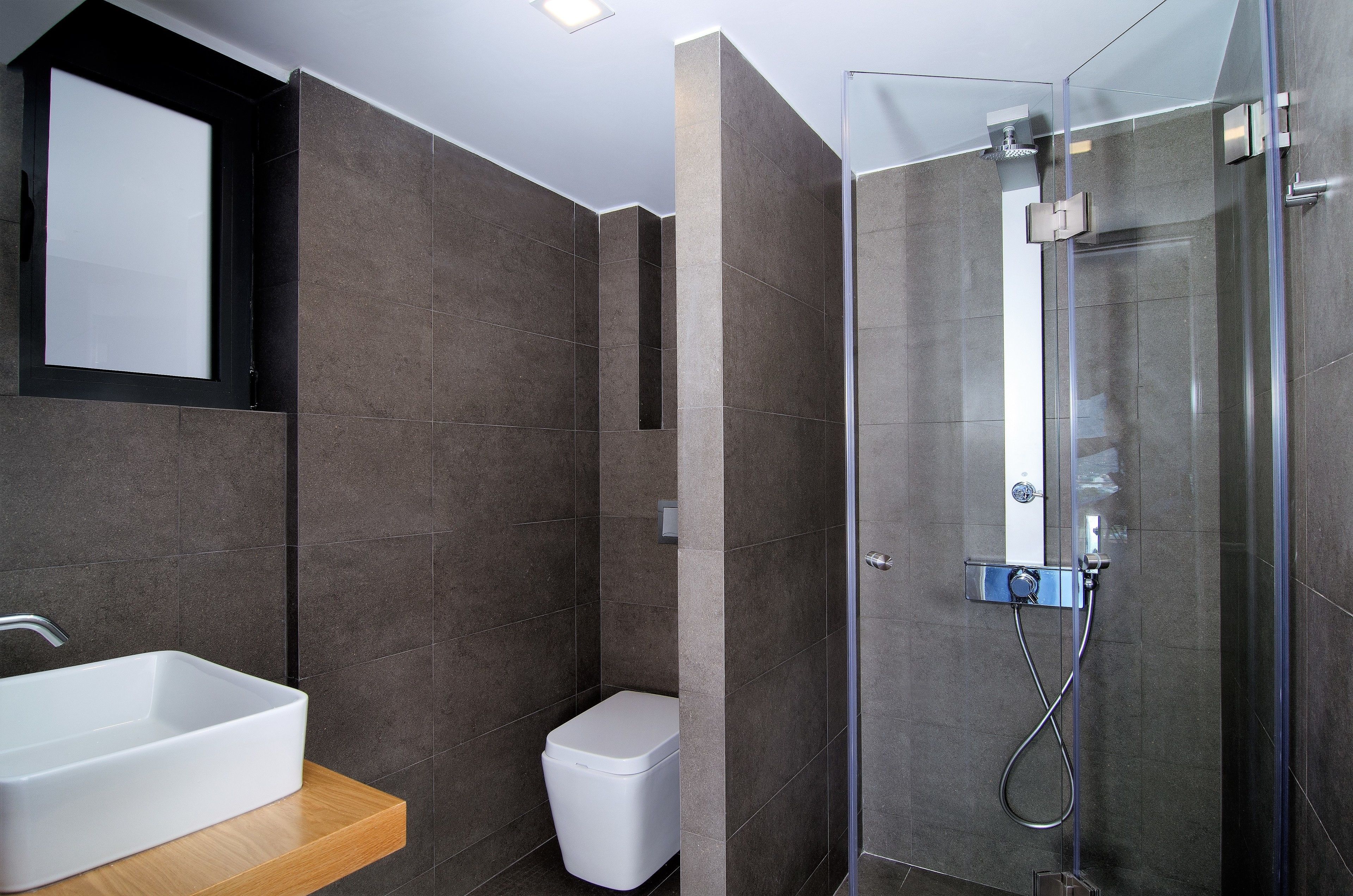 A modern bathroom with a rectangular sink, a toilet, and a glass-enclosed shower area.