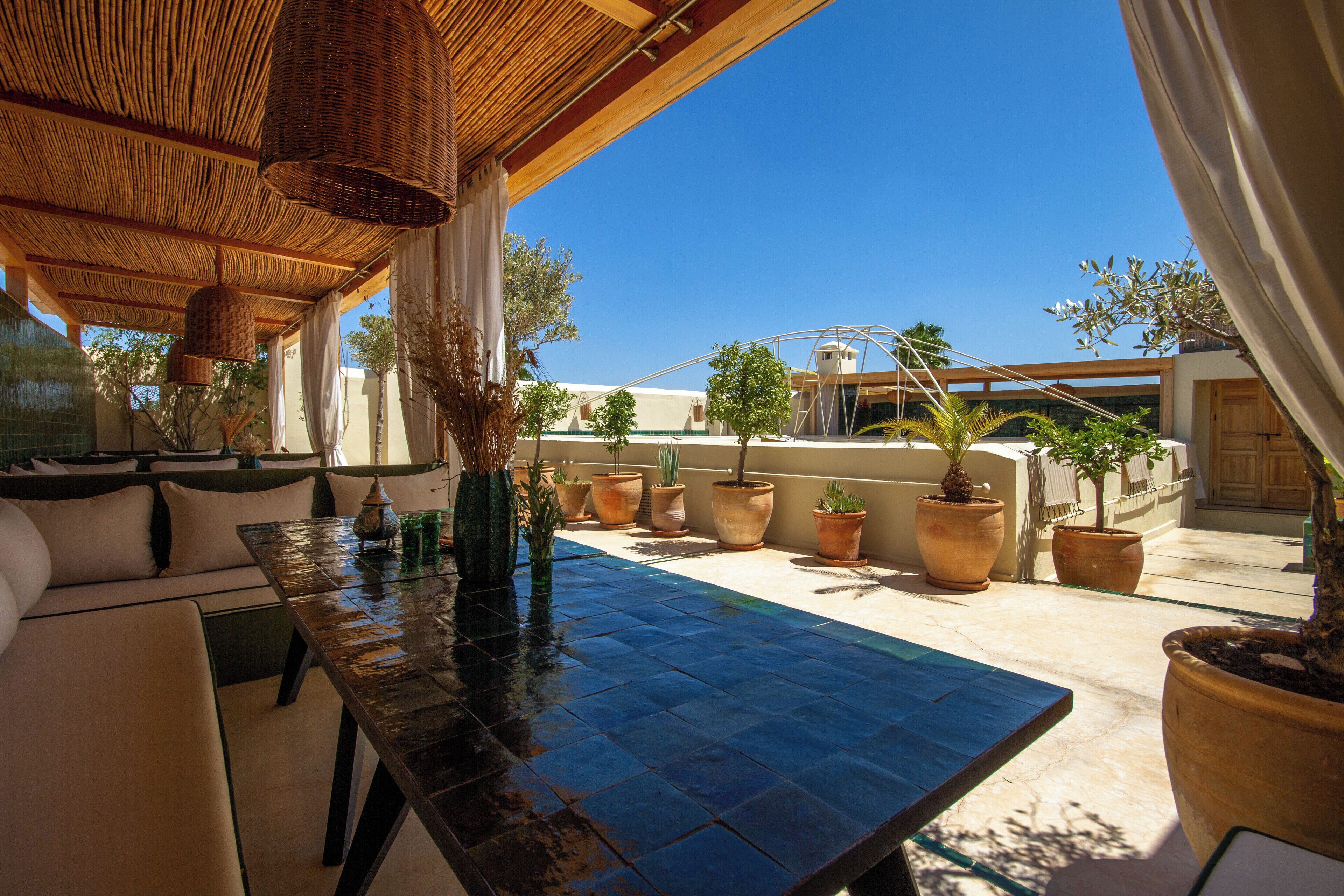 An outdoor patio with a wooden table, potted plants, and a seating area.