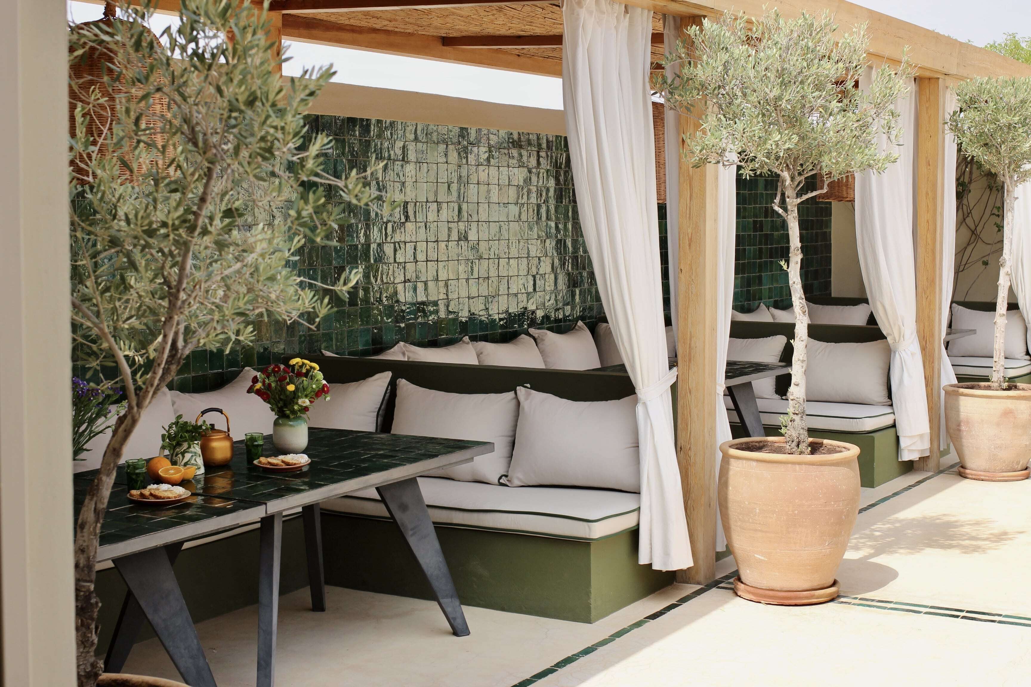 A covered outdoor seating area with a table, chairs, and potted plants.