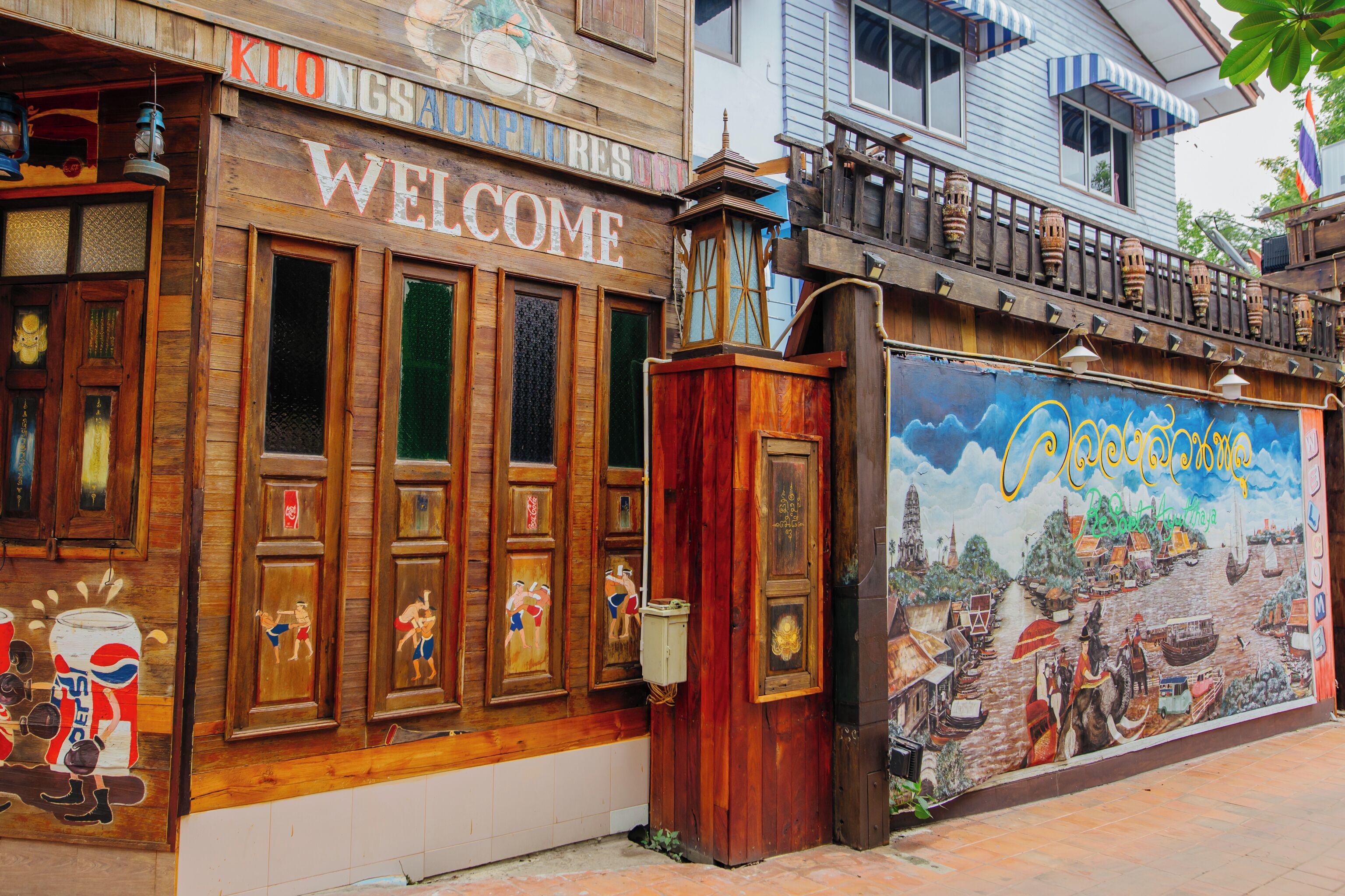 A wooden building with a 'WELCOME' sign and a mural depicting a historical scene.