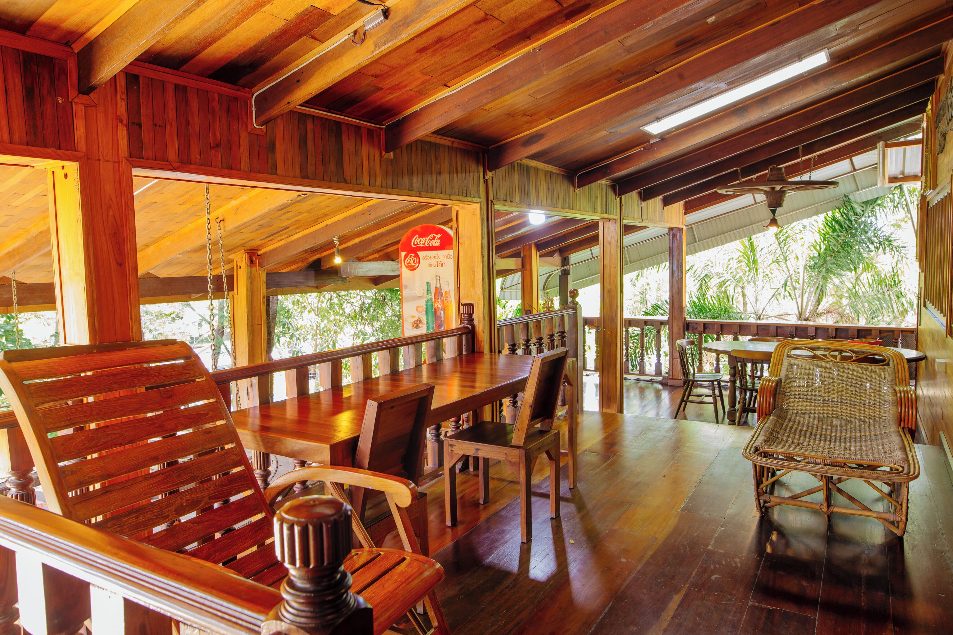 A wooden interior with a dining area featuring tables and chairs, a ceiling fan, and a Coca-Cola sign.