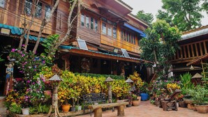A courtyard with wooden buildings, potted plants, and outdoor seating. - Klong Suan Plu Resort (Ayutthaya)