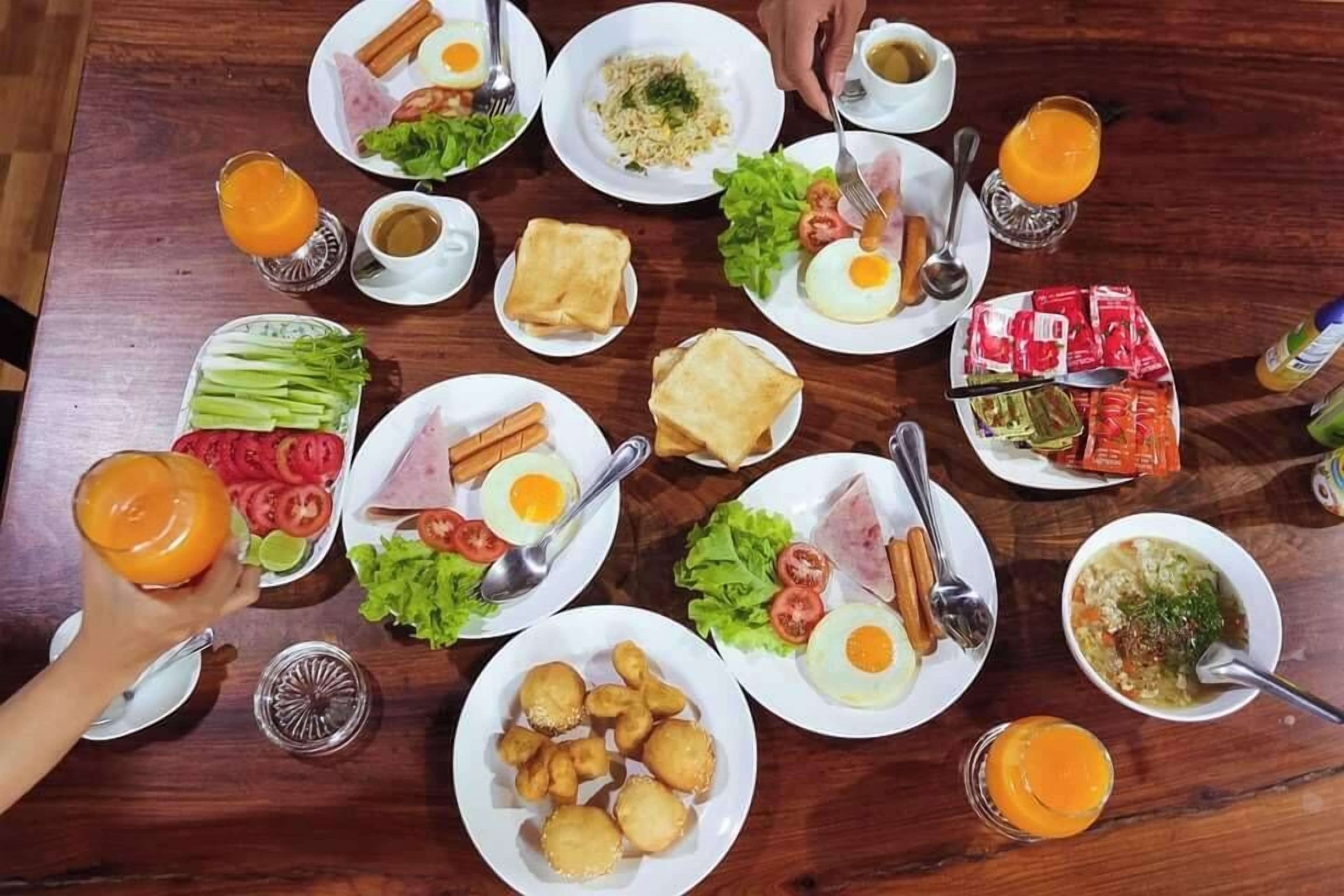 Une table dressée avec divers aliments pour le petit-déjeuner, notamment des œufs, des toasts et des fruits.