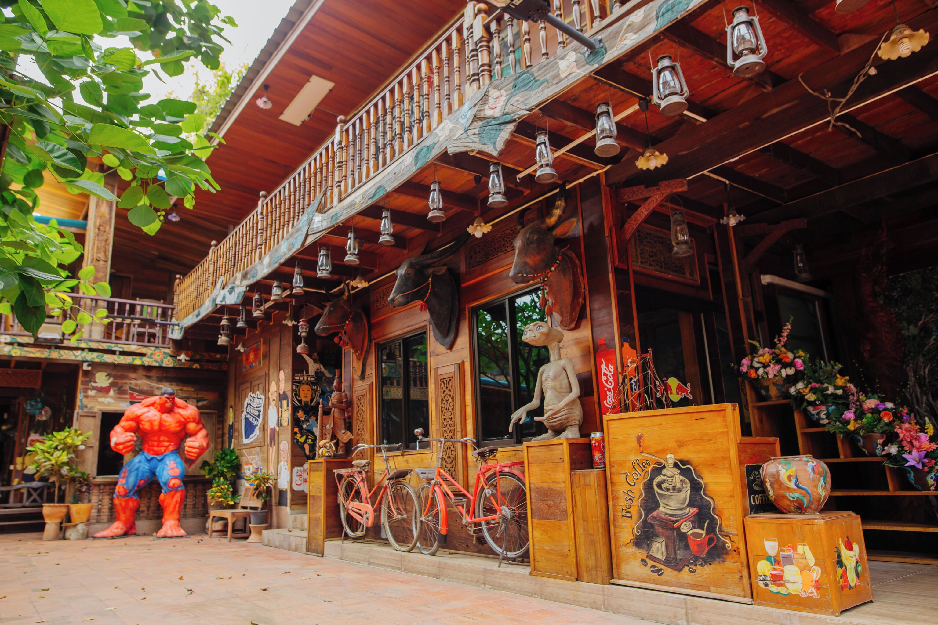 A building with a wooden facade, a balcony with hanging lanterns, and a statue of a bull.