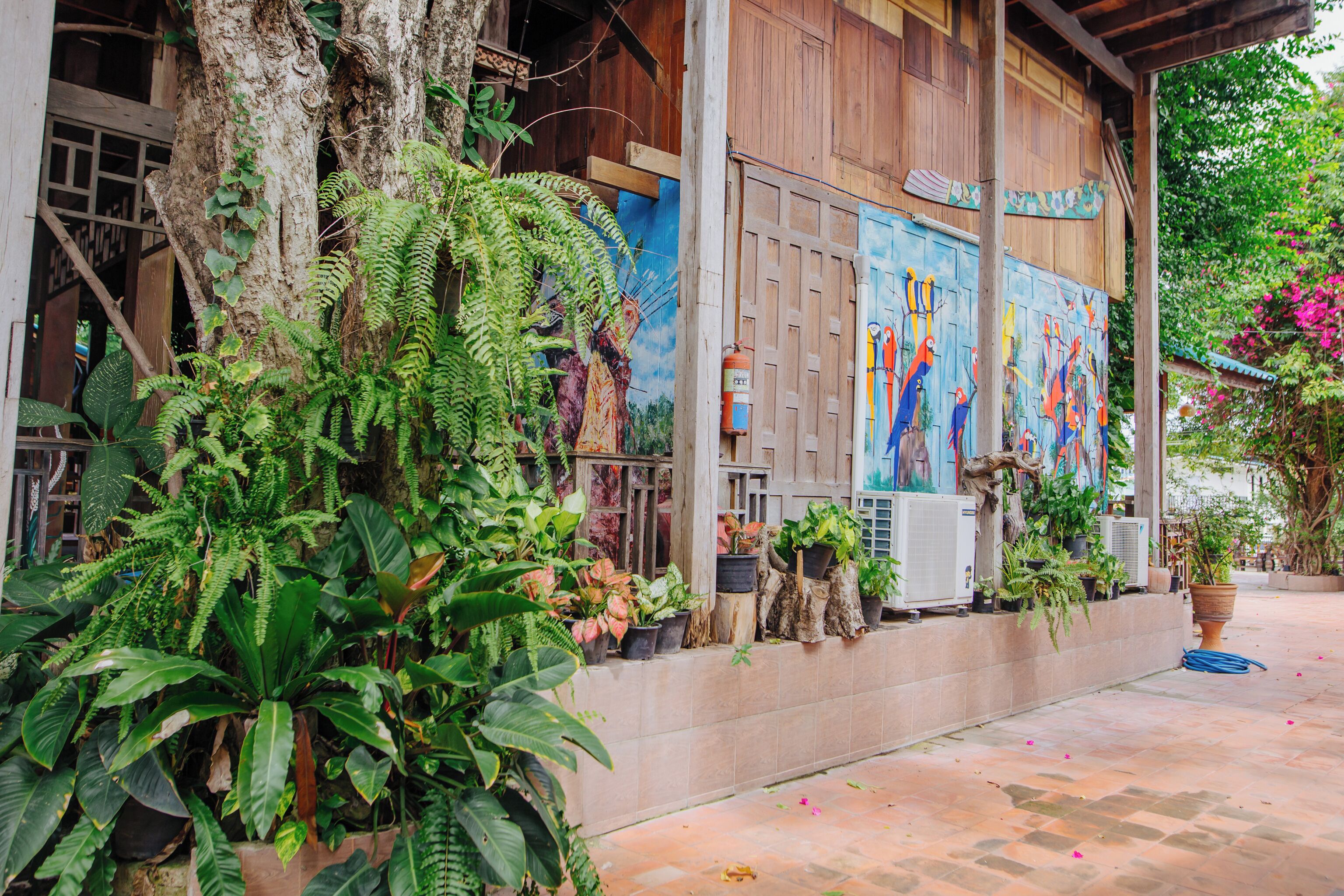 Um edifício com fachada de madeira, um mural e diversos vasos de plantas.