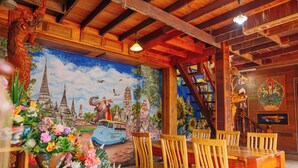 A wooden interior with a mural of a blue car and elephants, wooden chairs, and a staircase. - Klong Suan Plu Resort (Ayutthaya)