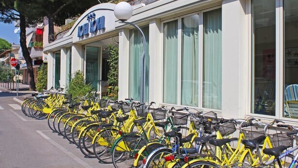 A row of yellow bicycles parked outside a building with a sign that reads "LOFT HOTEL". - Hotel Royal (Misano Adriatico)