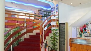 A staircase with wooden railings and red carpeted steps leading to a second floor. - Hotel Royal (Misano Adriatico)