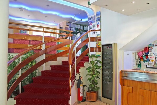 A staircase with wooden railings and red carpeted steps leading to a second floor.