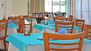 A restaurant with tables covered in blue tablecloths and wooden chairs. - Hotel Royal (Misano Adriatico)