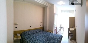 A hotel room with a bed, bedside table, and a small desk with a chair. - Hotel Royal (Misano Adriatico)